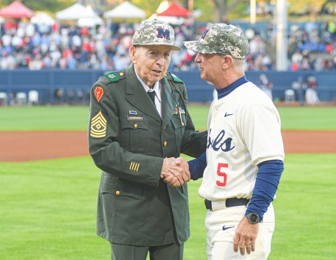 Army veteran Woody Lovejoy, left, shakes hands with Ole Miss head coach Mike Bianco (5) after throwing out the ceremonial first pitch before the game against Mississippi State at Swayze Field in Oxford, Miss., on Friday, Apr. 12, 2024.
