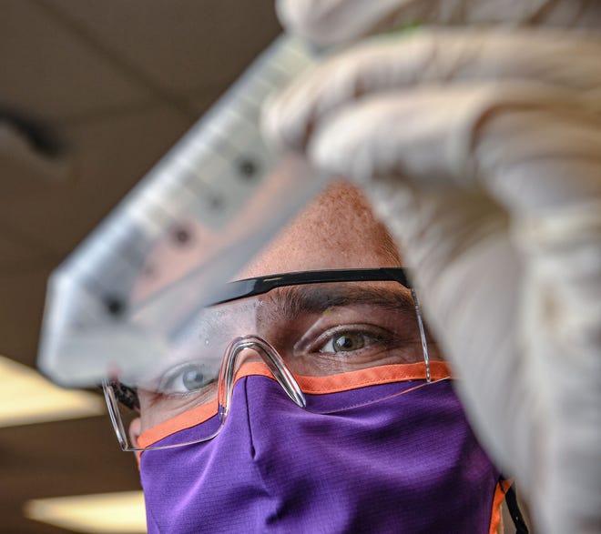 Jonathan Heywood, a Clemson University PhD student, looks at a sample of saliva ready for a robot to process in the COVID-19 Clinical Diagnostics Lab at Clemson University.
