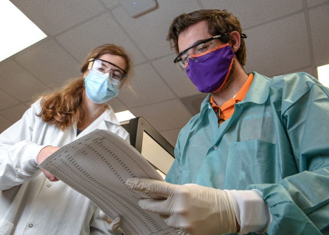 Rachel Ham, left, Clemson University lab supervisor, lets  Dylan Chitwood, a Clemson University Bioengineering PhD student, look over paperwork in the COVID-19 Clinical Diagnostics Lab at Clemson University.