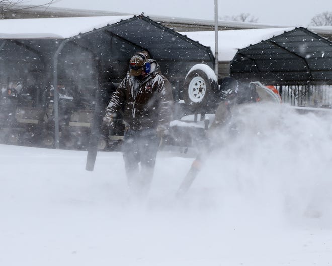 Two employees of The Mower Shop, use blowers to clear the driveway, Monday, Feb. 15, at the 3700 Towson Ave business.