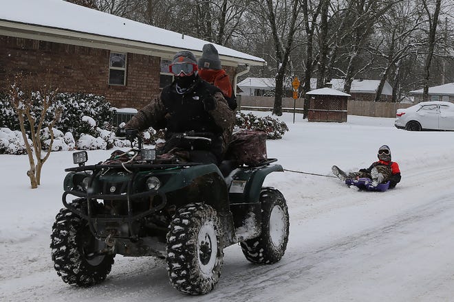 Friends use a 4-wheeler to go sledding on Massard Rd., Monday, Feb. 15, after snow blanketed the area overnight.