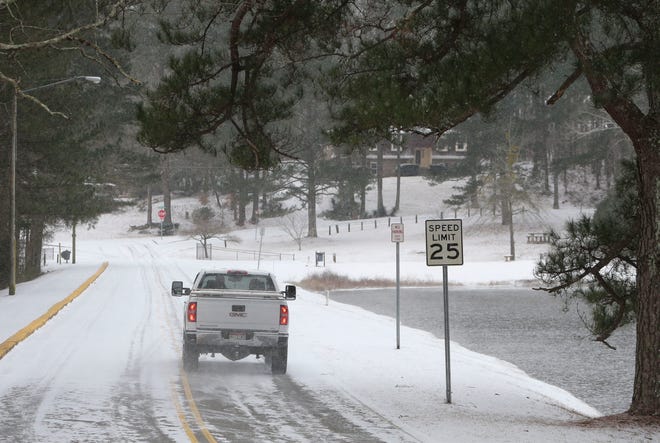 Snowfall greeted West Alabama residents Tuesday, Feb. 16, 2021. A motorist drives over the dam on Northwood Lake. [Staff Photo/Gary Cosby Jr.]