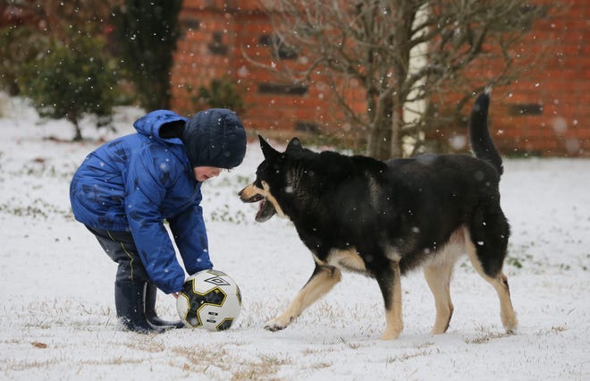 Snowfall greeted West Alabama residents Tuesday, Feb. 16, 2021. Grayson Hardin plays with his soccer ball and his dog Tink as they enjoy the rare snow day. [Staff Photo/Gary Cosby Jr.]