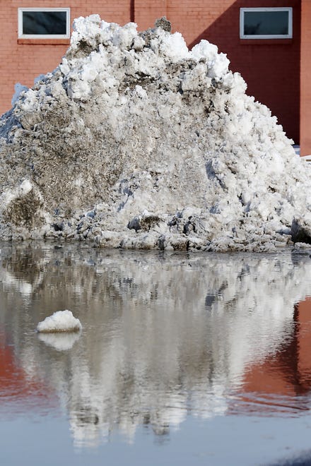 A pile of snow is reflected in its own melting pool in the Baptist Health Medical Plaza parking lot,1500 Dodson Ave., Thursday, Feb. 18, in Fort Smith.